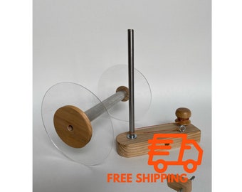 May include: Wooden yarn swift with clear plastic bobbins and a metal spindle. The swift has a wooden base with a small knob and a metal hook. The swift is used to wind yarn into a ball.