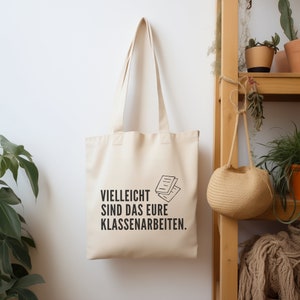 Baumwolltasche für Lehrkräfte mit dem Aufdruck Vielleicht sind das eure Klassenarbeiten mit einem Heft. Die Tasche ist 38cm breit, 42cm hoch und hat zwei 70cm lange Henkel. Hergestellt aus Bio Baumwolle