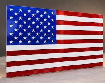 May include: A rectangular wall art piece featuring the United States flag with a glossy finish. The design displays a blue canton with white stars and alternating horizontal red and white stripes, presented in a clean, modern, and flat orientation.