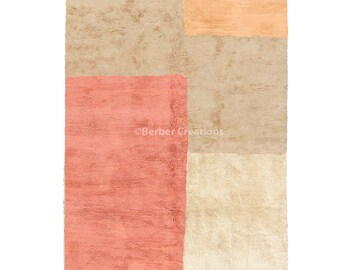 May include: A rectangular rug with a geometric design. The rug is made of wool and has a fringe border. The rug is beige, peach, and pink.