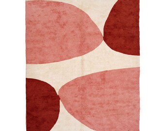 May include: A cream-colored rug with abstract shapes in shades of pink and red. The rug has a fringed edge and the text "Berber Creations" is printed in the bottom right corner.