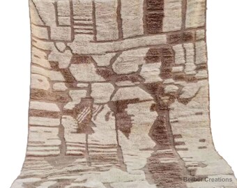 May include: A beige and brown Moroccan rug with a geometric pattern. The rug has a fringe border and is made of wool.