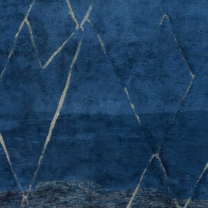 May include: A blue rug with a geometric pattern of white lines. The rug has a soft, plush texture.