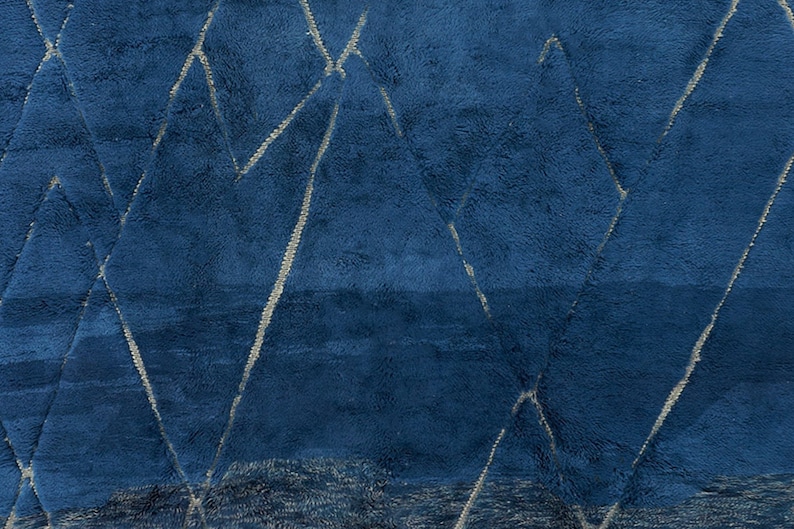 May include: A blue rug with a geometric pattern of white lines. The rug has a soft, plush texture.