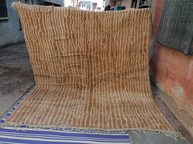 Puede incluir: Una alfombra grande, rectangular, de color marr&oacute;n y crema con un patr&oacute;n tejido. La alfombra tiene un borde de flecos.