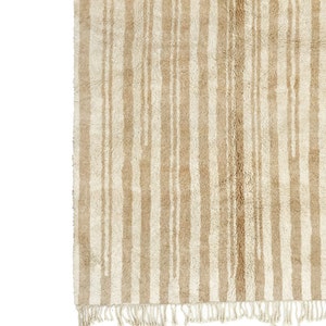 May include: A beige and white striped rug with a fringe border. The rug has a subtle, textured pattern.