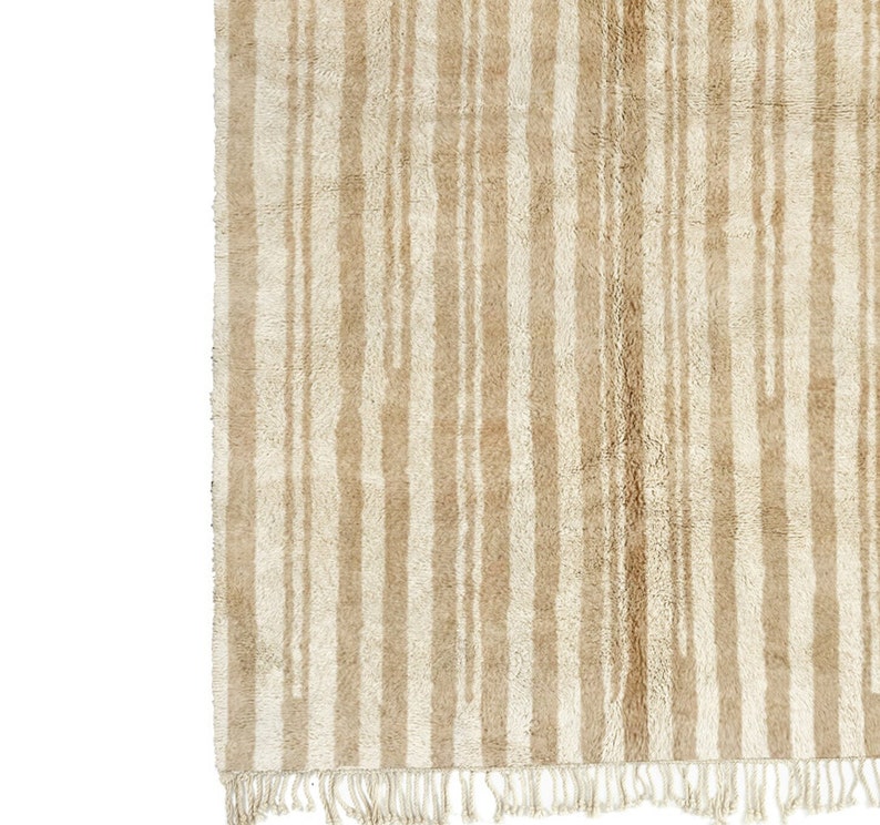 May include: A beige and white striped rug with a fringe border. The rug has a subtle, textured pattern.