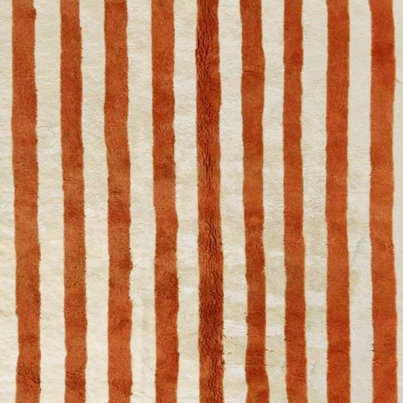 May include: A close-up of a striped rug with alternating white and orange stripes. The rug has a soft, fuzzy texture.