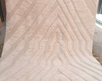 May include: A white, hand-woven rug with a geometric pattern. The rug has a fringe border and is made of wool.