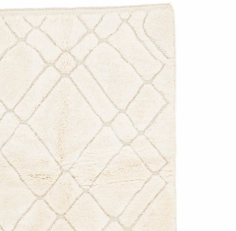 May include: A white rug with a diamond pattern woven into the fabric. The rug has a subtle sheen and a soft, plush texture.