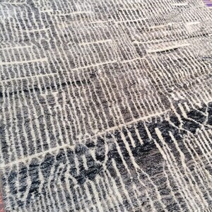 May include: A black and white patterned rug with a geometric design. The rug is made of wool and has a soft, plush texture.