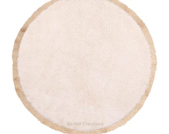 Pode incluir: Um tapete redondo creme com uma superfície texturizada e uma borda bege. O tapete tem uma aparência macia e felpuda, adequado para vários estilos de decoração de casa. O texto "Berber Creations" é visível na parte inferior.