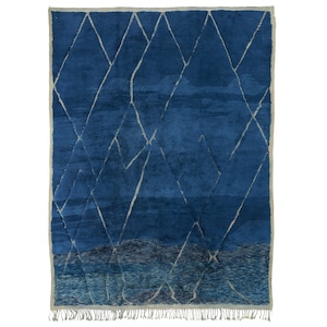 May include: A blue and white Moroccan rug with a geometric pattern. The rug has a fringe border.