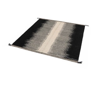 May include: Black and white handwoven rug with a vertical stripe down the centre. The rug has a gradient pattern with the black colour fading into white.