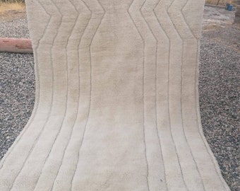 May include: A white woven rug with a geometric pattern. The rug has a fringe border and is made of natural fibers.
