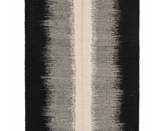 May include: Black and white handwoven rug with a vertical white stripe in the center. The rug has a gradient pattern, fading from black to white.