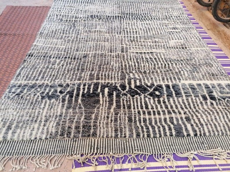 May include: A black and white patterned rug with a fringe border. The rug has a geometric design with vertical lines and a wavy pattern.