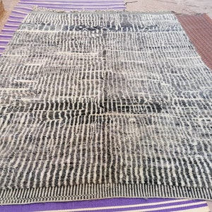 May include: A black and white striped rug with a geometric pattern. The rug is made of wool and has a soft, fluffy texture.
