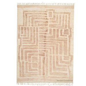 Puede incluir: Una alfombra beige con un patr&oacute;n geom&eacute;trico en un tono beige m&aacute;s claro. La alfombra tiene un borde de flecos y el texto "Berber Creations" est&aacute; impreso en la esquina inferior derecha.