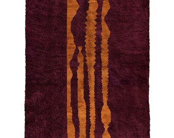 Könnte beinhalten: Ein burgunderfarbener Wollteppich mit einem Muster aus orangefarbenen vertikalen Streifen. Der Teppich hat einen Fransenrand und der Text "Berber Creations" ist in der rechten unteren Ecke gedruckt.