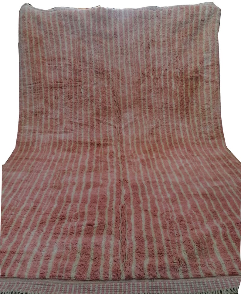May include: A pink and white striped rug with a fringed border. The rug is made of wool and has a soft, plush texture.