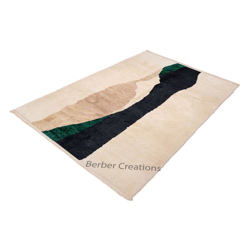 Pu&ograve; includere: Un tappeto beige con un designo astratto in nero e verde. Il tappeto ha un bordo a frangia e il testo "Berber Creations" &egrave; stampato nell'angolo in basso a destra.