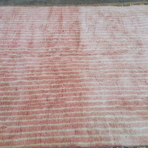 May include: A pink and white striped rug with a fluffy texture.