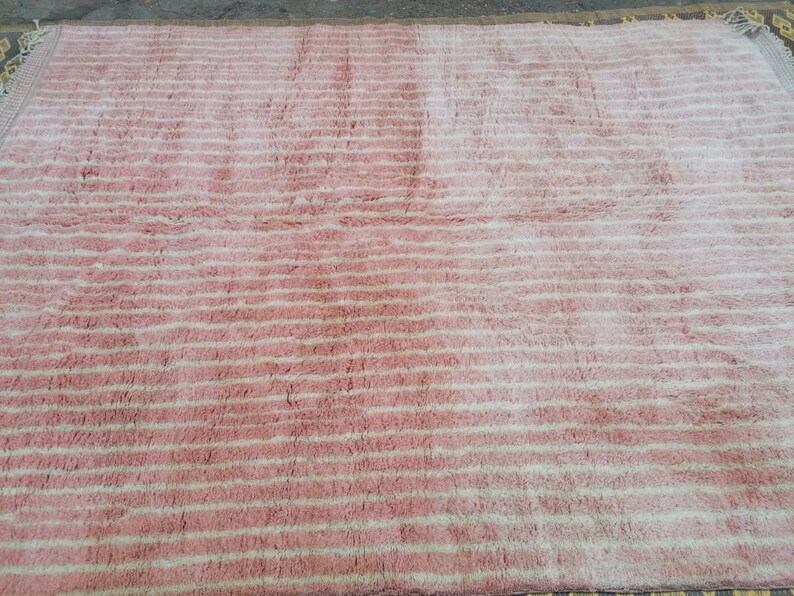 May include: A pink and white striped rug with a fluffy texture.