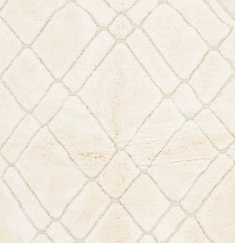 May include: A white rug with a diamond pattern woven into the fabric. The rug has a soft, fluffy texture.