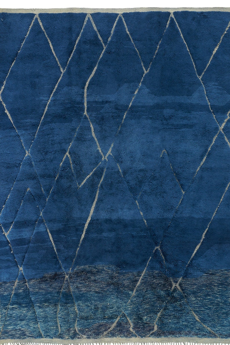 May include: A blue rug with a geometric pattern of white lines. The rug has a gradient effect, with the blue color becoming lighter towards the bottom.