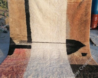 May include: A hand-woven rug with a geometric design in shades of brown, black, white, and red. The rug has a fringe border and is made of wool.
