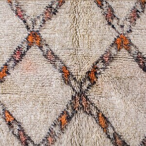 May include: A white rug with a diamond pattern in shades of orange, black, and pink.