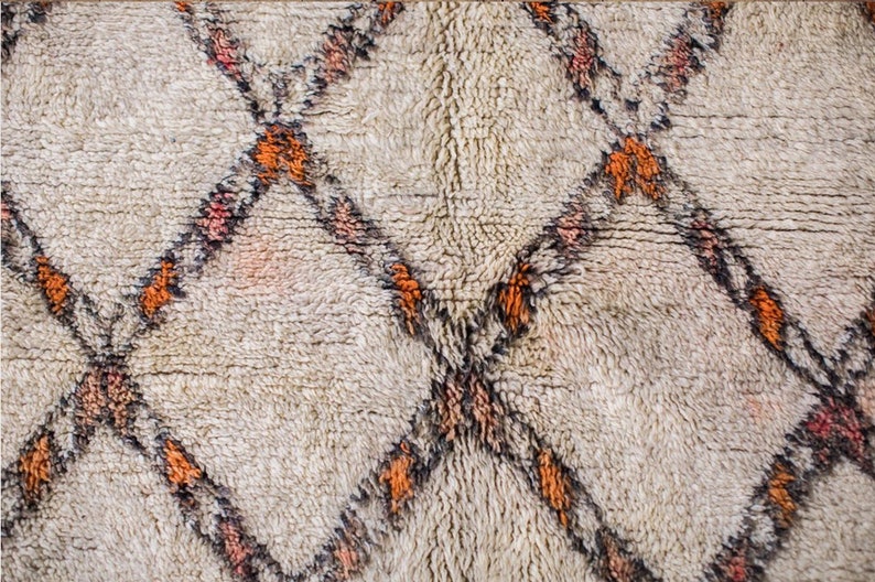 May include: A white rug with a diamond pattern in shades of orange, black, and pink.