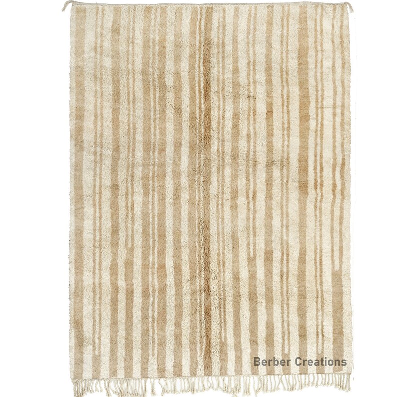 May include: A cream-colored rug with a vertical striped pattern in a slightly darker shade of cream. The rug has a fringe border.