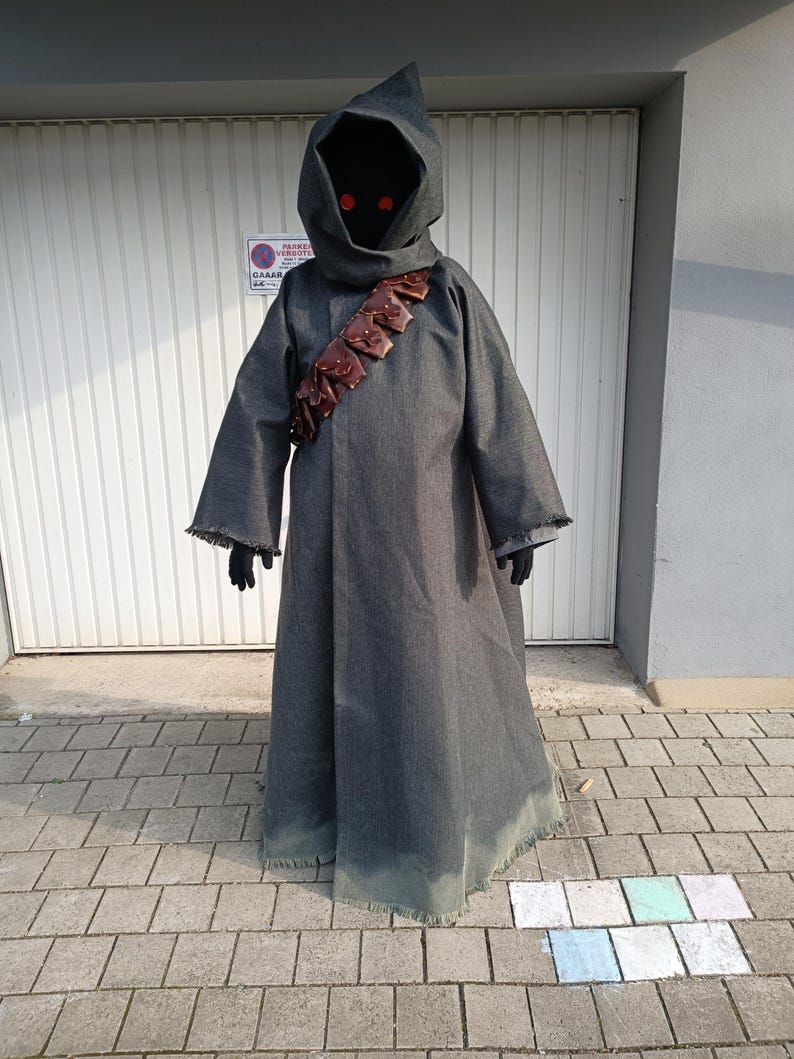 May include: A full-length dark gray hooded robe featuring a frayed hem and wide sleeves. A brown leather bandolier with multiple small pouches is worn diagonally across the chest. The hood is deep and dark, revealing two glowing red circular eyes.
