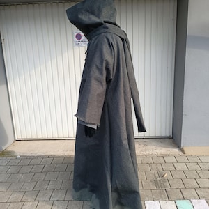May include: A floor-length, dark gray hooded robe with long, wide sleeves and a frayed hemline. The garment features a structured hood and a simple, loose-fitting silhouette that extends to the ground, covering the entire body from head to toe.