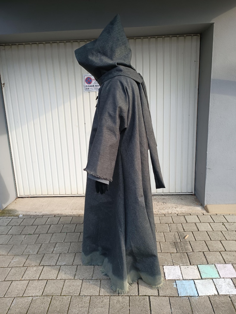 May include: A floor-length, dark gray hooded robe with long, wide sleeves and a frayed hemline. The garment features a structured hood and a simple, loose-fitting silhouette that extends to the ground, covering the entire body from head to toe.