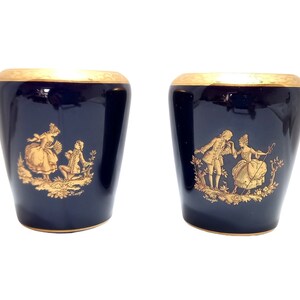 Könnte beinhalten: Zwei blaue und goldene Porzellanvasen mit goldenen Szenen von Paaren in einem Garten.
