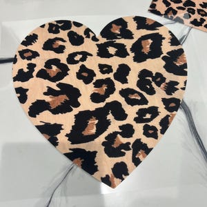 May include: A heart-shaped fabric patch with a leopard print pattern in shades of brown, black, and beige.