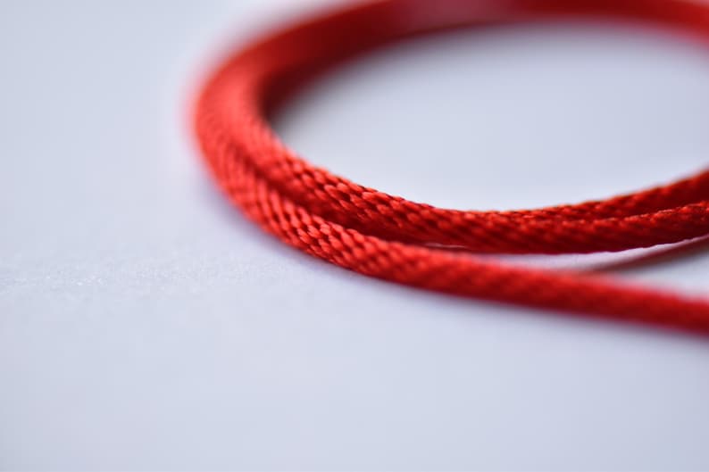 Macro close-up of vibrant red braided silk cord — detailed weave texture showing durability and flexibility for everyday wear.
