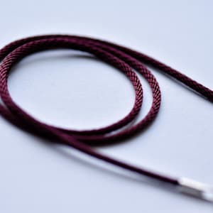 Puede incluir: Primer plano de un cordón marrón, un tipo de cuerda que se utiliza para hacer joyas.