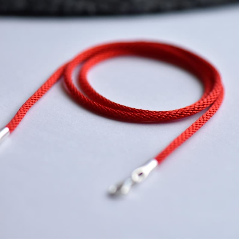 Close-up of red braided silk necklace cord with silver ends — vivid color and fine texture, perfect for pendants or minimalist layering.