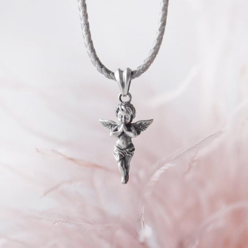 Romantic silver angel pendant with finely detailed wings and praying pose, highlighted against a dreamy feather background, perfect for heartfelt gifting