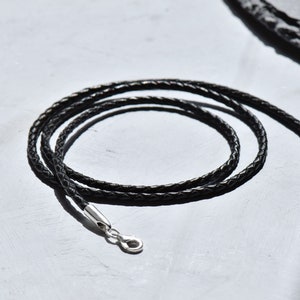 Detailed texture of a black braided leather necklace cord with a shimmering silver clasp, exuding sophistication and versatility for your jewelry collection