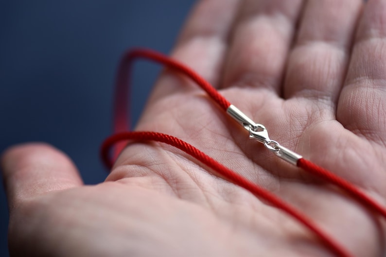 Hand holding a red braided silk cord with sterling silver clasp — vibrant color meets artisan texture, ideal for pendants or minimalist layering necklaces.
