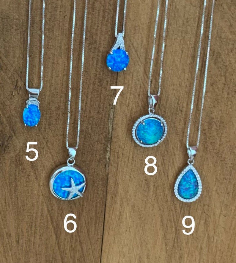 May include: Nine silver necklaces with blue opal pendants. The pendants feature different designs, including a teardrop, a circle with a starfish, and a circle with a starburst.
