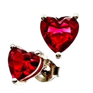 May include: A pair of heart-shaped earrings with red gemstones set in silver.