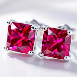 Pode incluir: Um par de brincos de pressão de prata com pedras preciosas vermelhas quadradas.