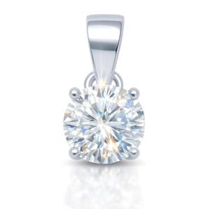 May include: A round, brilliant-cut clear gemstone pendant set in a four-prong silver-toned metal setting. The pendant features a smooth, tapered bail at the top, designed for attachment to a necklace chain, with a highly reflective, polished finish.