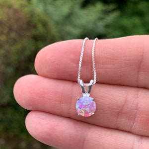 May include: A silver chain necklace with a round pink opal pendant.
